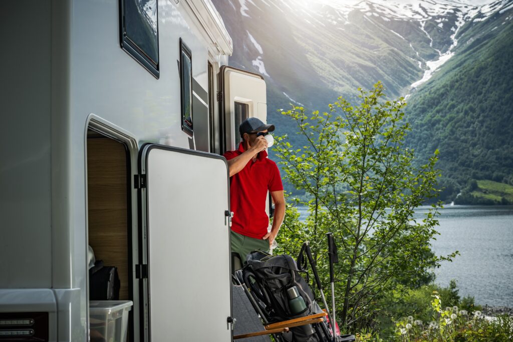 Mann drikker kaffe utenfor campingbil.